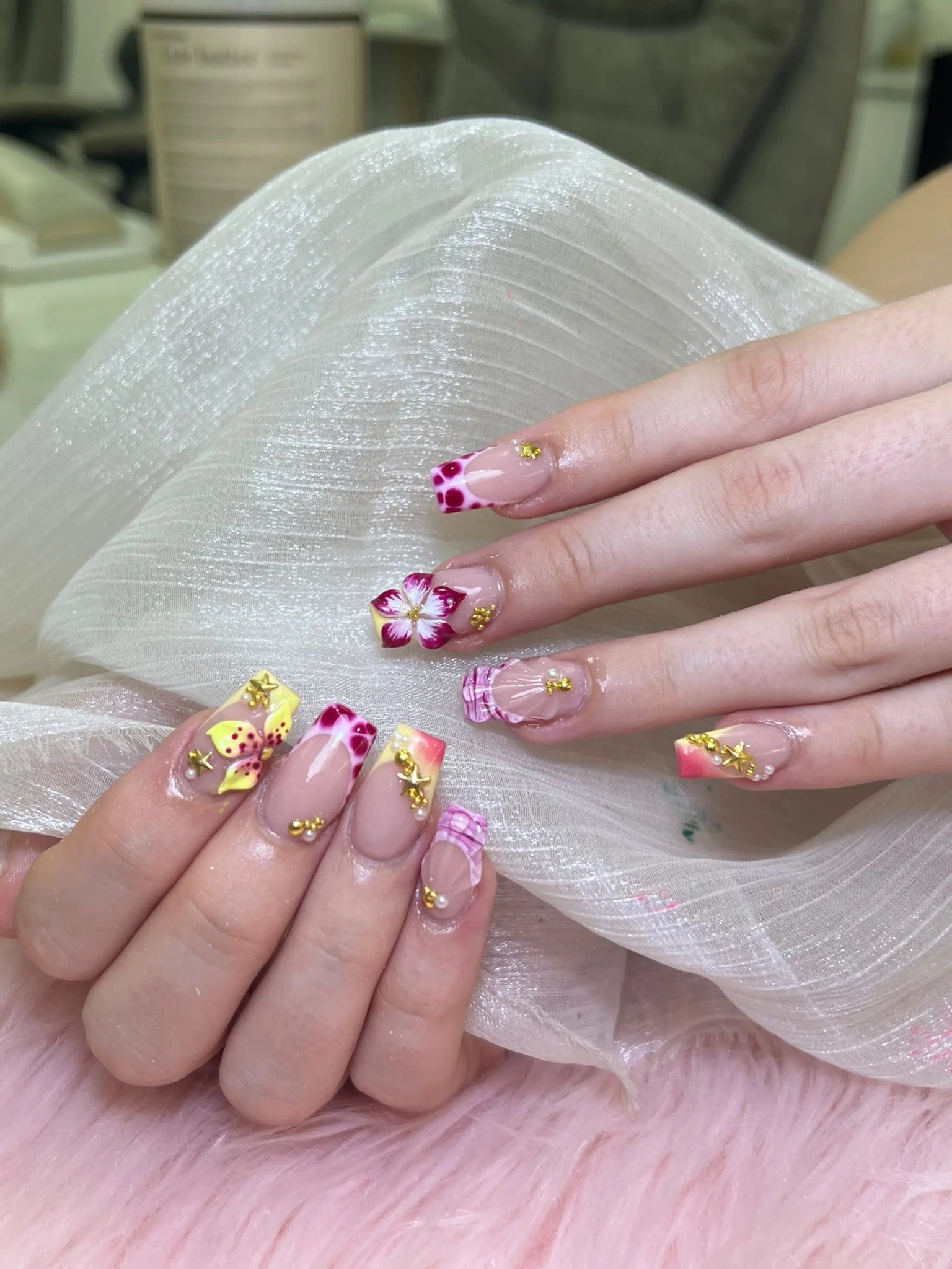 Nude nails with pink and yellow flowers and gold foil